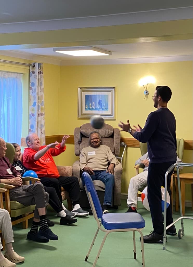 Alex leading a seated ball-toss activity with care home residents