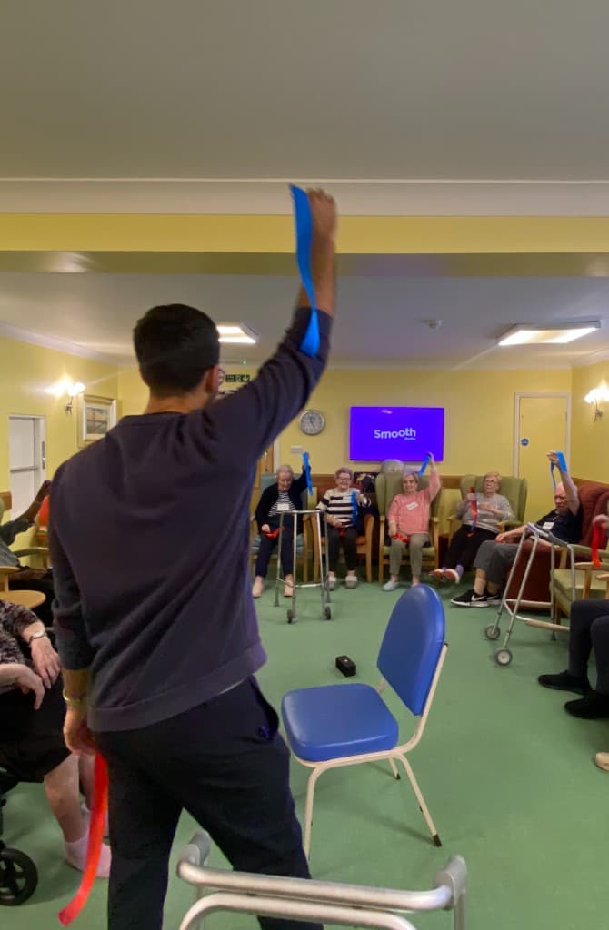 Care home residents using ribbons in a physiotherapist-led exercise class