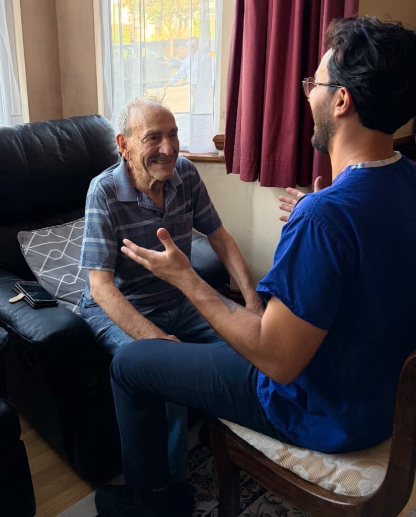 Alex speaking with a smiling client during a home physiotherapy visit